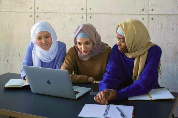 Three women studying in front of one laptop