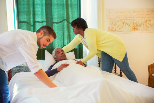 Two aged care professionals tucking a client into bed